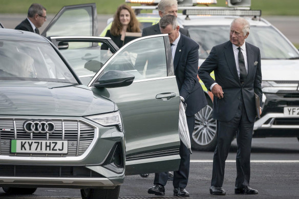 Britain’s King Charles III, right, waits as an assistant opens an umbrella for Camilla, the Queen Consort, left, as they arrive at Aberdeen Airport to travel to London.