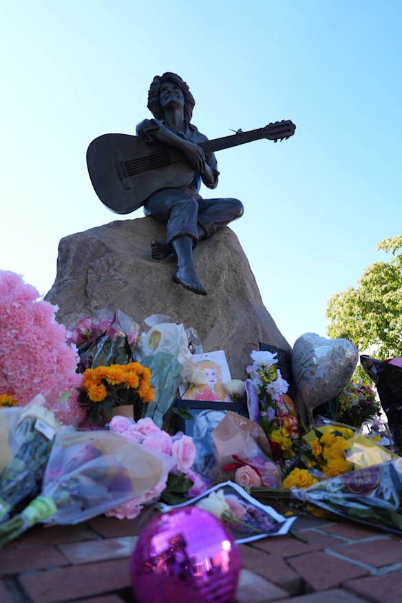 Floral tributes pile up at the base of the statue of Dolly Parton in Sevierville, Tennessee.