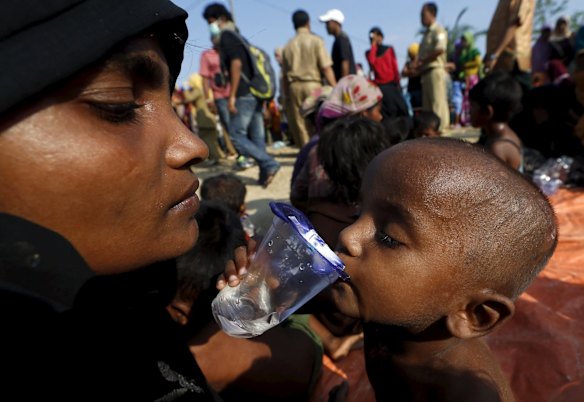 A Rohingya migrant mother watches as her child drinks water after they arrived by boat at the port of Julok village in Kuta Binje, Indonesia's Aceh Province, May 20, 2015. Hundreds of Rohingya and Bangladeshi migrants landed in Indonesia's northwestern Aceh province early on Wednesday, an Indonesian search and rescue official said. 