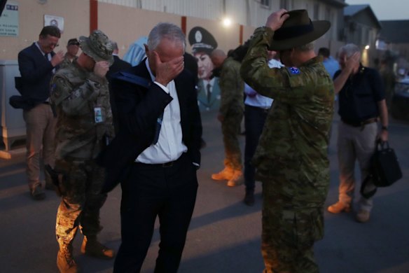 Prime Minister Malcolm Turnbull protects his eyes from rotar wash as Blackhawk helicopters land at the Resolute Support Mission HQ Kabul, Afghanistan.