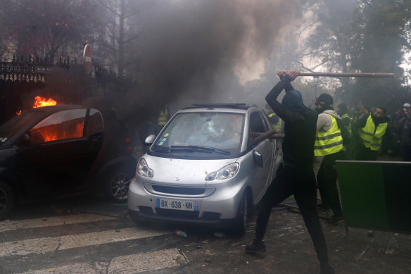 Hooded demonstrators smash a car during a demonstration.