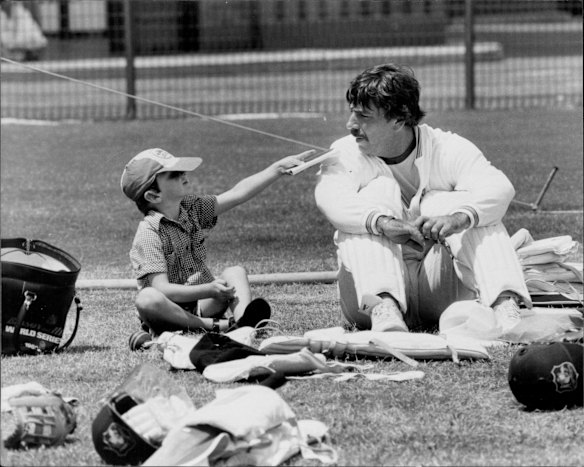 Australian cricket team practices at SCG. Rod Marsh is requested to sign the autograph book of a fan, John Albert, 5, of Ringwood, Melbourne, January 1982. 