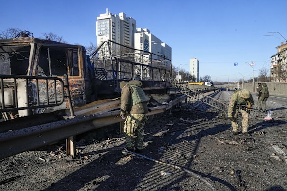 Ukrainian soldiers investigate debris of a burning military truck on a street in Kyiv on Saturday. Street fighting broke out as Russians pushed towards the capital. 