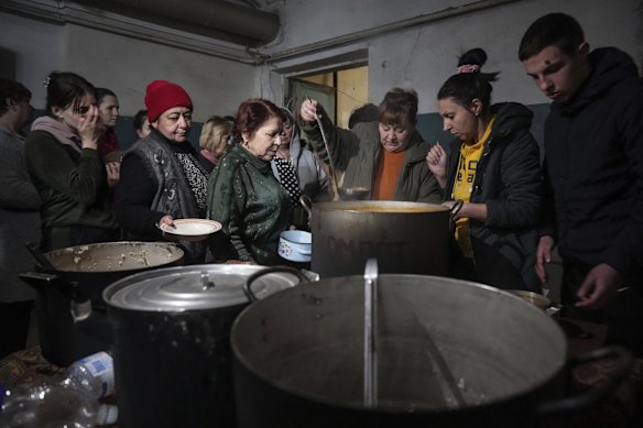 People queue to receive hot food in an improvised bomb shelter in Mariupol, Ukraine.