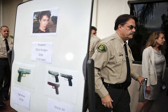 Santa Barbara County Sheriff Bill Brown, right, walks past a board showing the photos of suspected gunman Elliot Rodger and the weapons he used.