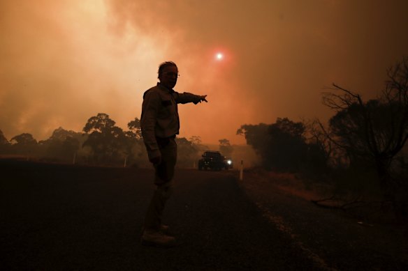Chris Collins point to wear his home is as the North Black Range bushfire threatens properties at Bombay, NSW.