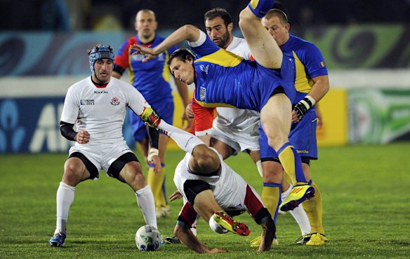 Romania's Iulian Dumitras (top) and Georgia's Lasha Khmaladze fall to the ground after contesting a high ball.