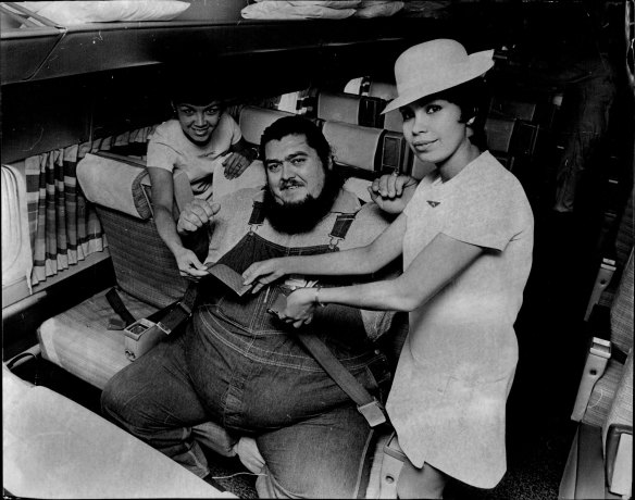 “When American wrestler Haystack Calhoun left Sydney today for Hong Kong, it took two hostess and two normal airline seats to fit him into Philippine Airlines DC8 jet. The hostesses are Teresita Fernandez, 28, and Dolores Gomez, 28, of Manila. December 7, 1971.”