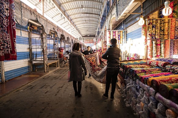 A vendor shows a rug to a customer inside the main bazaar in Kashgar, Xinjiang autonomous region, China.