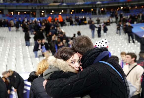A supporter comforts a friend after bombs were heard close to the Stade de France stadium at the end of the international friendly soccer match between France and Germany in Saint Denis just outside Paris. French President Francois Hollande says he is closing the country's borders and declaring a state of emergency after several dozen people were killed in a series of unprecedented terrorist attacks.