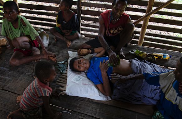 Sabodame Sebado, suffering from an untreatable liver condition with her family looking on, her husband rubs stinging nettle leaves on stomach to help manage the pain.