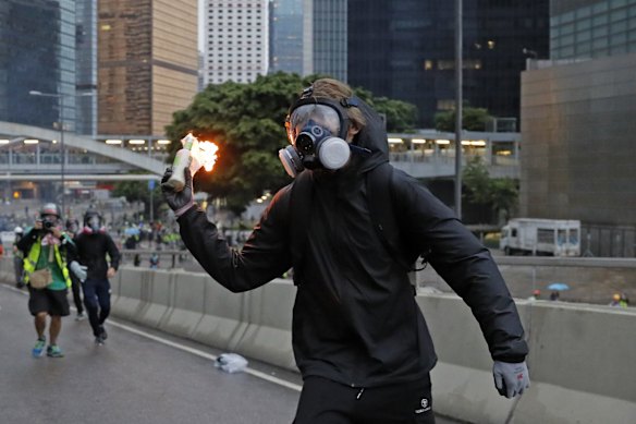 A protester prepares to throw a molotov cocktail towards police officers.