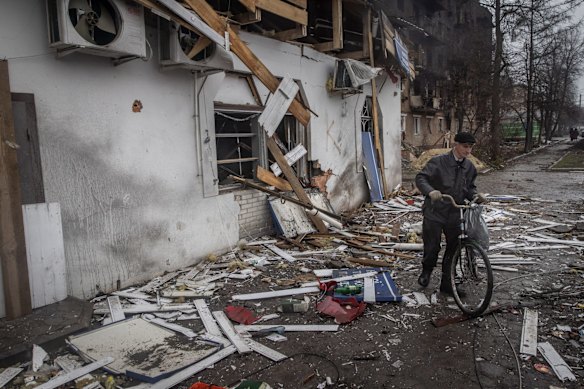 A man pushes his bike through debris from a destroyed shop close to the central train station that was used as a Russian base in Trostyanets.