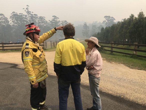 Captain John Lardner speaking with Graham and Bec Jones at the entrance to their property in Nana Glen on Tuesday.