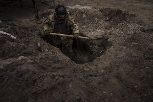 A Ukrainian soldier digs a foxhole in Irpin.