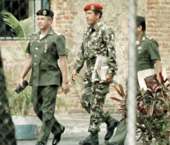In this Feb. 5, 1992 file photo, paratroop commander Hugo Chavez, center, is escorted by military intelligence officers after being arrested for trying to overthrow Venezuela's government in a coup.
