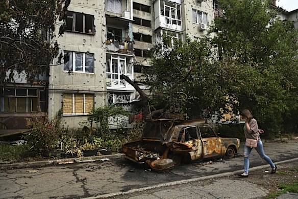 A woman walks past the remains of a vehicle in front of an apartment building where three people were killed in a missile strike. One man was burnt to death, one Ukrainian soldier was killed and another injured among others in Slovyansk, Ukraine. 
