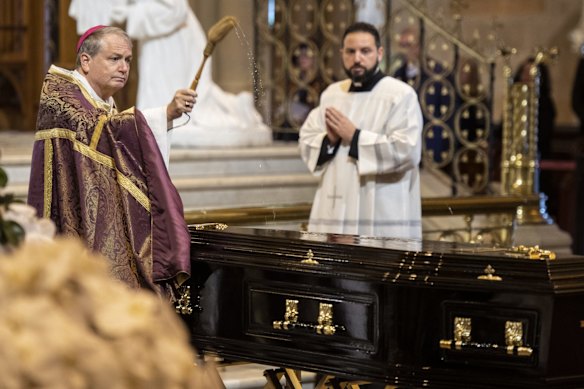 The Archbishop blesses the casket with holy water.