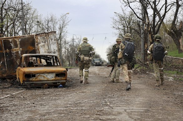 Servicemen of Donetsk People's Republic militia walk past damaged vehicles during a heavy fighting in an area controlled by Russian-backed separatist forces in Mariupol.