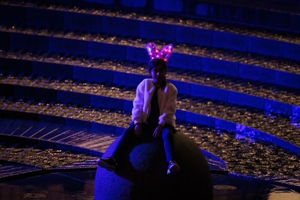 A young girl sits in the The Darling Harbour Woodward Water Feature as Vivid lights up for 2022  