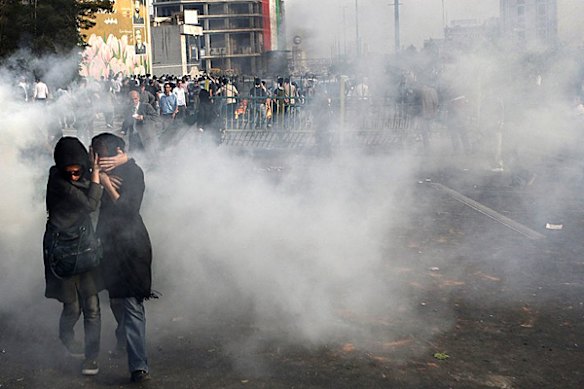 In this photograph posted on the internet, two Iranian women take cover from a cloud of either tear gas or smoke at an anti-government protest in Tehran, Iran Saturday June 20, 2009. 