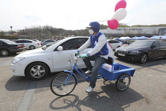 A man wearing a face mask rides a bicycle to deliver eggs to Christians before a drive-in worship service to celebrate an Easter at a public parking lot in Seoul, South Korea.