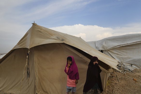 Two girls stand in front of a tent in Al-Hawl camp in North East Syria. 