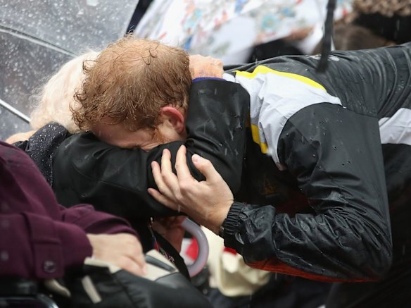 Prince Harry hugs 97 year old Daphne Dunne during a walkabout in the torrential rain at the Overseas Passenger Terminal on June 7, 2017 in Sydney, Australia.