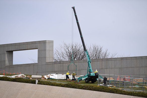 Workers are seen putting up new fence panels outside Parliament House.