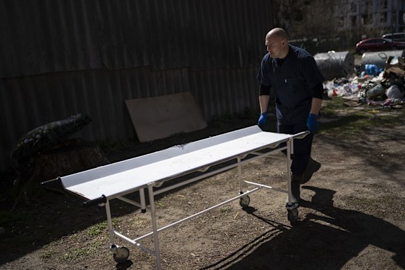 A volunteer pushes a stretcher towards a refrigerated area holding bodies of civilians killed in Bucha.