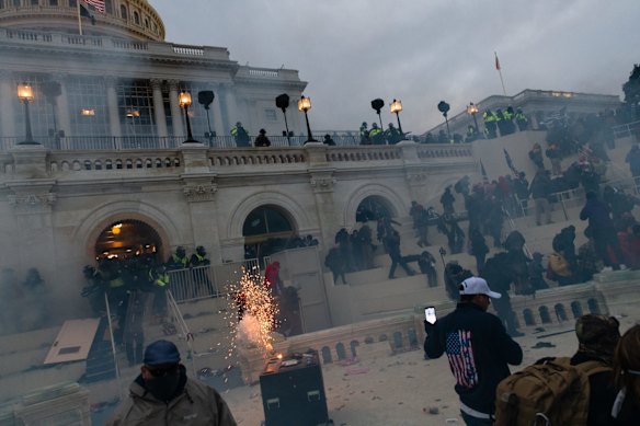 A flashbang grenade explodes as law enforcement officers push back demonstrators.