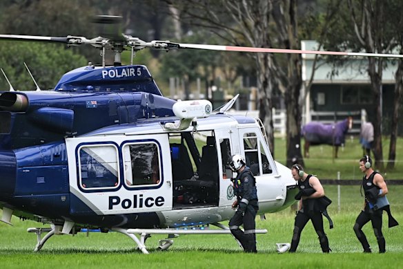 A police dive team take bottles to a POLAIR helicopter at Cobbity where a man's body was located in a vehicle after being washed away in floodwaters.