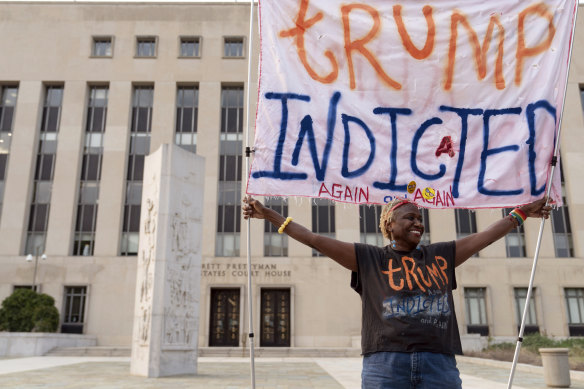 Protester Nadine Seiler holds a banner outside federal court.