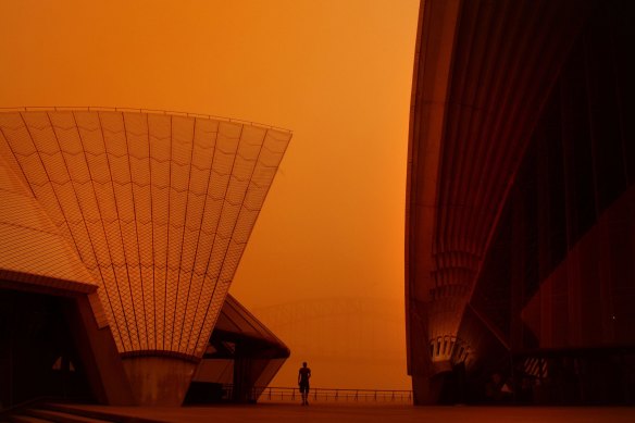 A man is dwarfed by the sails of the Opera House as a blanket of red dust covers the city in 2018.