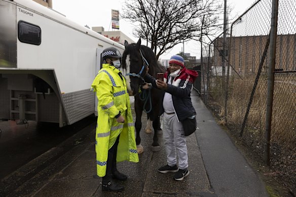 A Mounted Police Officer waiting for a break in the weather takes a photo with a pedestrian in Liverpool.