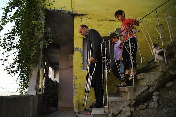 Wafa Gourani 47 a dessert chef from Aleppo (left) walks down the steps followed by his two youngest sons Hamza Gourani, aged 6 years old (centre) and Abdullah Gourani, aged 8 years old (right) at their rented family apartment in Istanbul. Wafa lost his leg in an airstrike in 2015. He remembers the airstrike that injured him when he was walking down the street close to his home, shopping for the evening meal for his family. They fled Syria and have been living in Istanbul where Wafa's two eldest sons are working to provide for the family. Wafa is a patient at the Kuwait Istanbul Orthotic-Prosthetic Center in Istanbul which provides Syrian refugees who have lost limbs in the Syrian war with free prosthetics that they make with high-tech scanners. 
