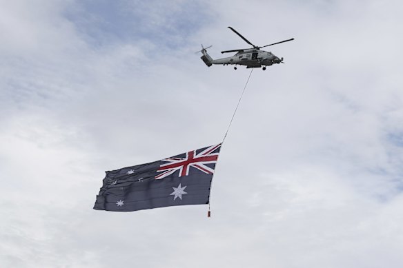 A helicopter with an Australian flag doing a flypast over Lake Burley Griffin during the flag raising and citizenship ceremony at Rond Terrace in Canberra.
