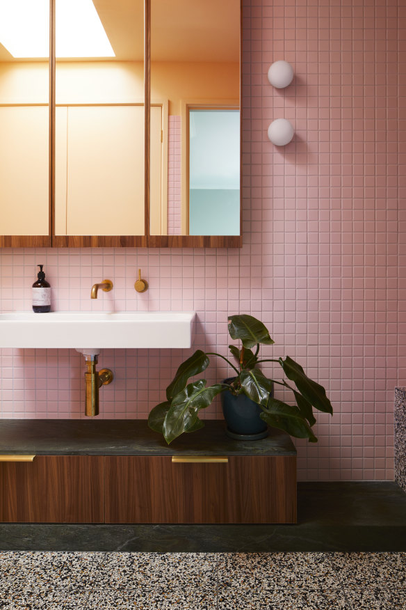 New finishes in the upstairs family bathroom include pink wall tiles and brass tapware grounded by walnut veneer, stone benches and a terrazzo floor. 