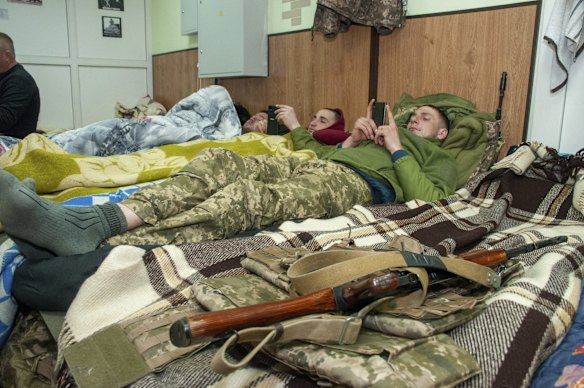 Ukrainian servicemen rest with their weapons within arm's reach in Kharkiv.