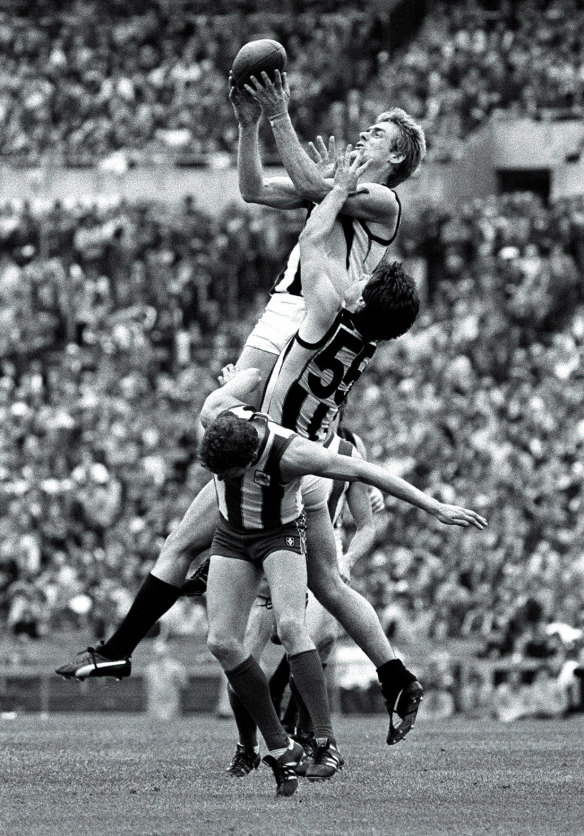 Collingwood ruckman Peter Moore soars over team-mate Mark Dreher and North’s Maurice Boyse. 