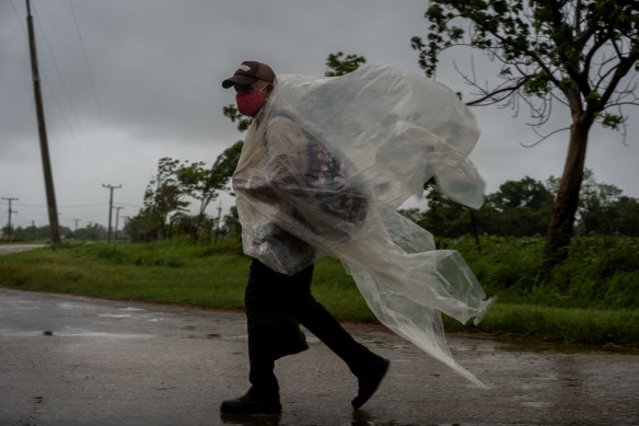A man uses pieces of plastic to protect against the rain caused by Hurricane Ida.