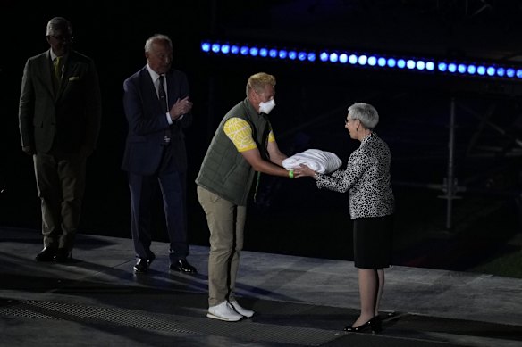 Australian athlete Barrie Lester hands the flag to Victorian Governor Linda Dessau.