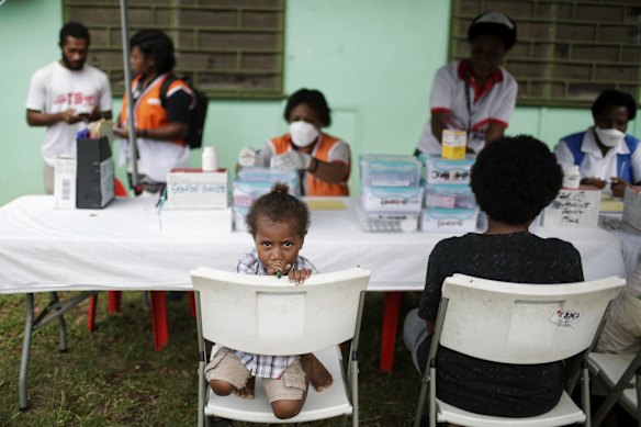 A young girl with her mother waiting to receive tuberculosis medication at the 6-mile health clinic. 