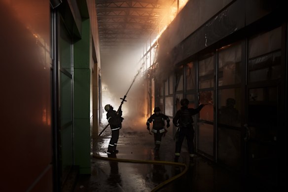 Firefighters work to extinguish a fire at a shop following a Russian bombardment in Kharkiv.