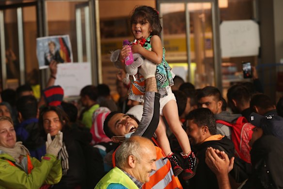 A volunteer worker holds up a child who was among approximately 800 migrants who had arrived on a train from Hungary at Munich Hauptbahnhof main railway station in Munich, Germany. 