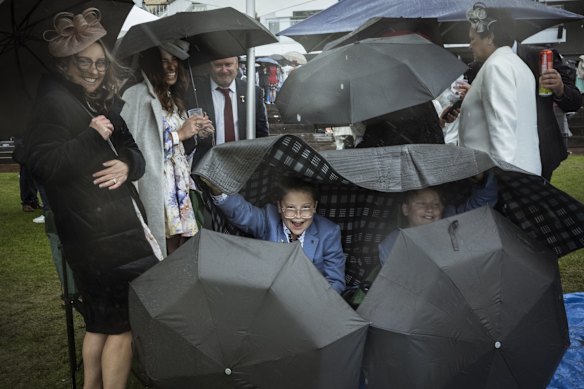 Racegoers brave the rain at Flemington Racecourse.