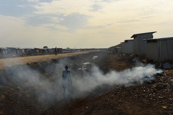 A woman pauses from collecting anything that can be used to fuel a fire, in one of the drainage trenches in the UN Bentiu Protection of Civilian's site that have been dug to prevent mass flooding in the rainy season. Women are in danger of attacks when they go outside the POC to collect firewood.