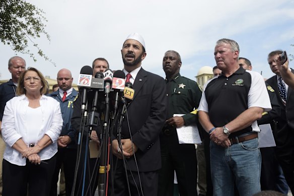 Imam Muhammad Musri, center, president of the Islamic Society of Central Florida, addresses reporters while flanked by members of law enforcement and community leaders during a news conference.