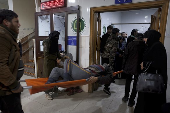 People carry a man injured in an earthquake into the al-Rahma Hospital in Darkush, in Syria's north.