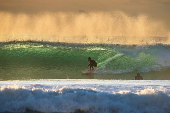 Surfers use the growing swell along the Sydney coast. This afternoon it will grow to near 15 feet.
